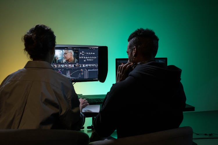 Back View Of Man And Woman Sitting And Working On Computer