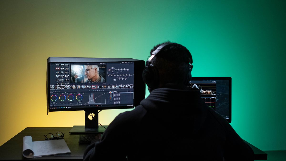 Video editor working on dual monitors with headphones
