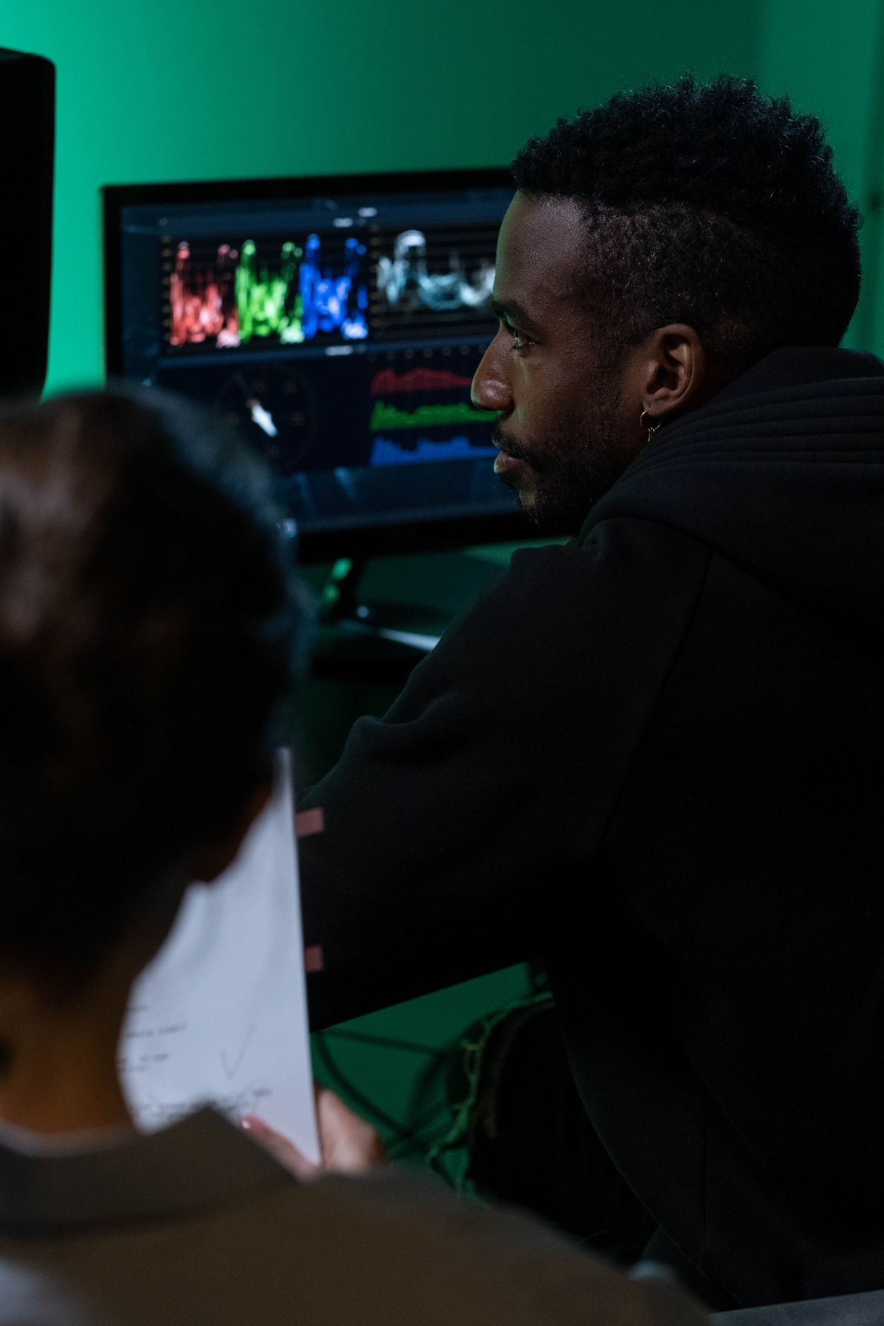 Man looking at a computer screen showing graphs, seen from behind