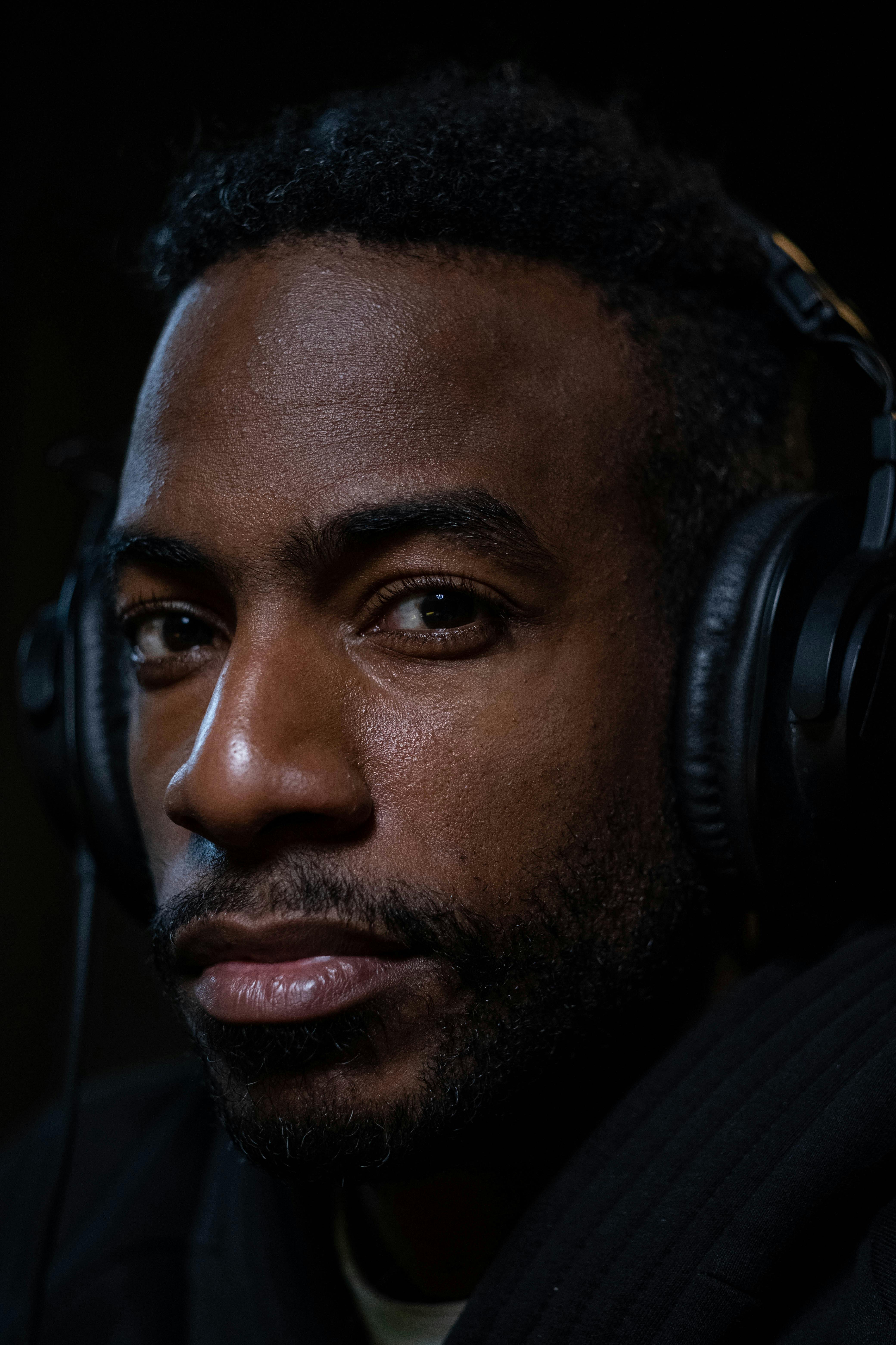 Free Close-up of a man with headphones, showcasing an intense expression for a modern portrait. Stock Photo