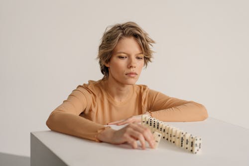 Woman Arranging Domino on a White Table 