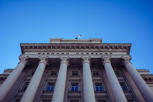 A Flag on Top of a Concrete Building with Pillars