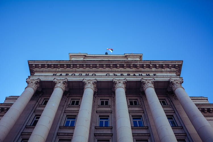 A Flag On Top Of A Concrete Building With Pillars