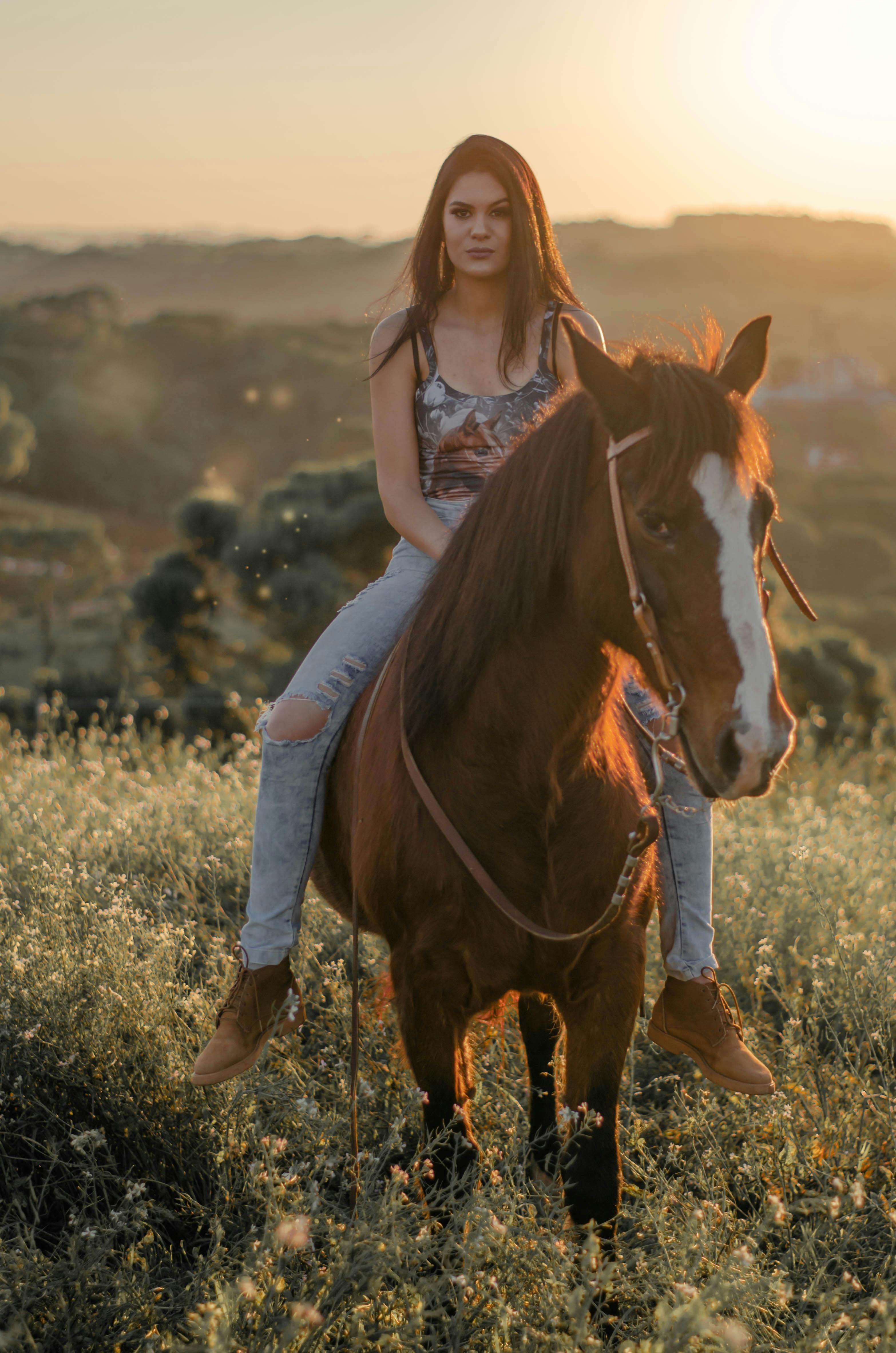 A cowgirl riding a horse through a field during a stunning sunset in Caxias do Sul, Brazil.