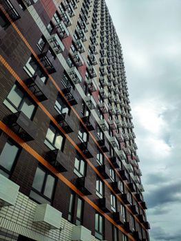 Impressive vertical shot of a modern skyscraper in Russia showcasing a geometric facade and cloudy sky.
