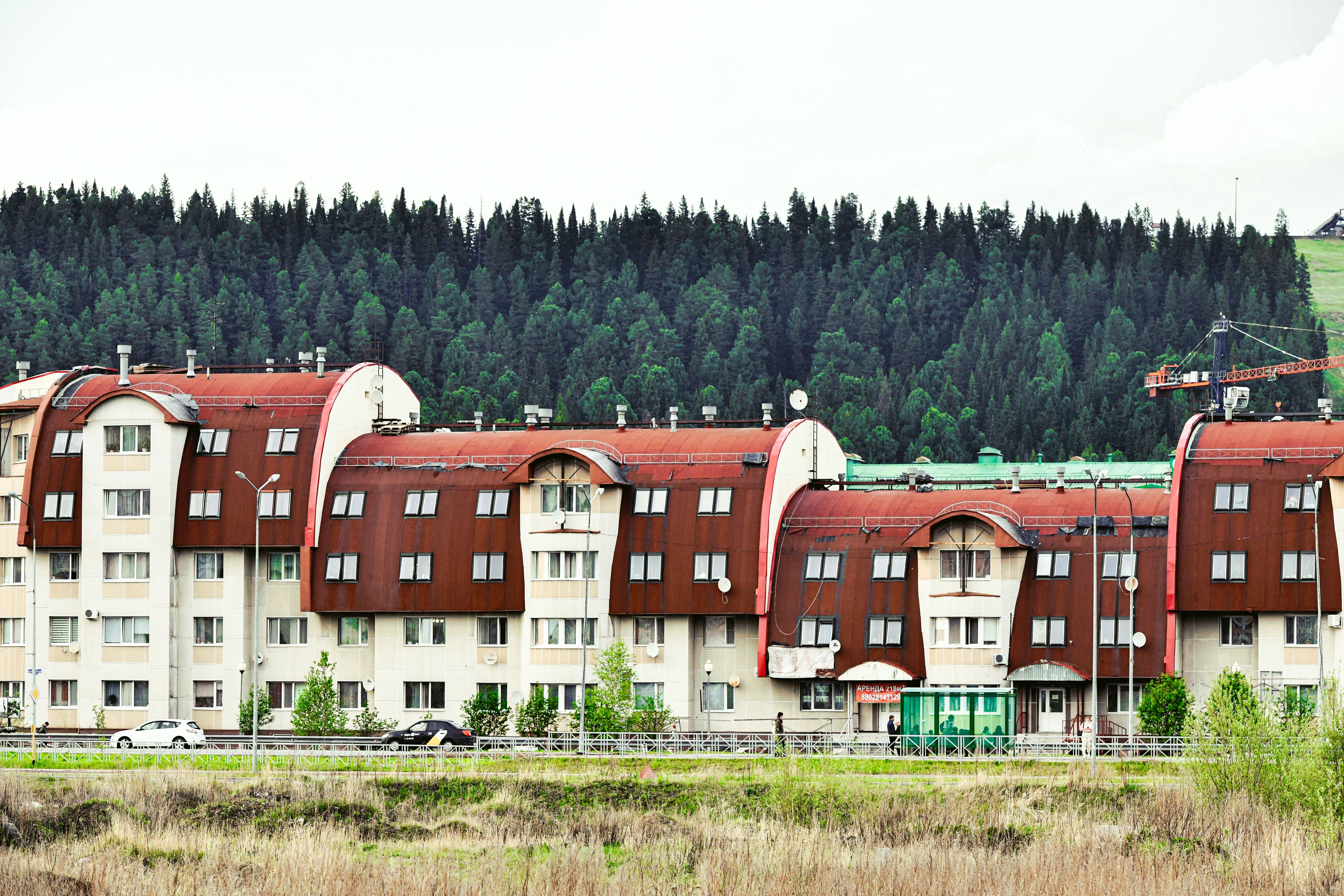 Contemporary apartment complex with unique architecture set against a lush forest backdrop.