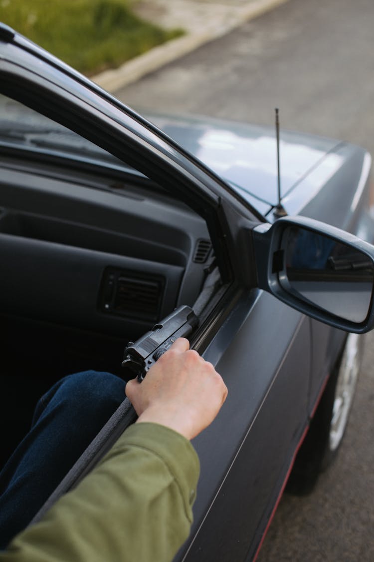 A Person Holding Gun In The Car