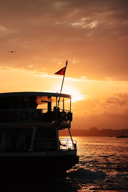 Boat with a Flag at Sea during Sunset