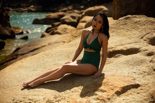 A Woman wearing Bathing Suit Sitting on the Rock