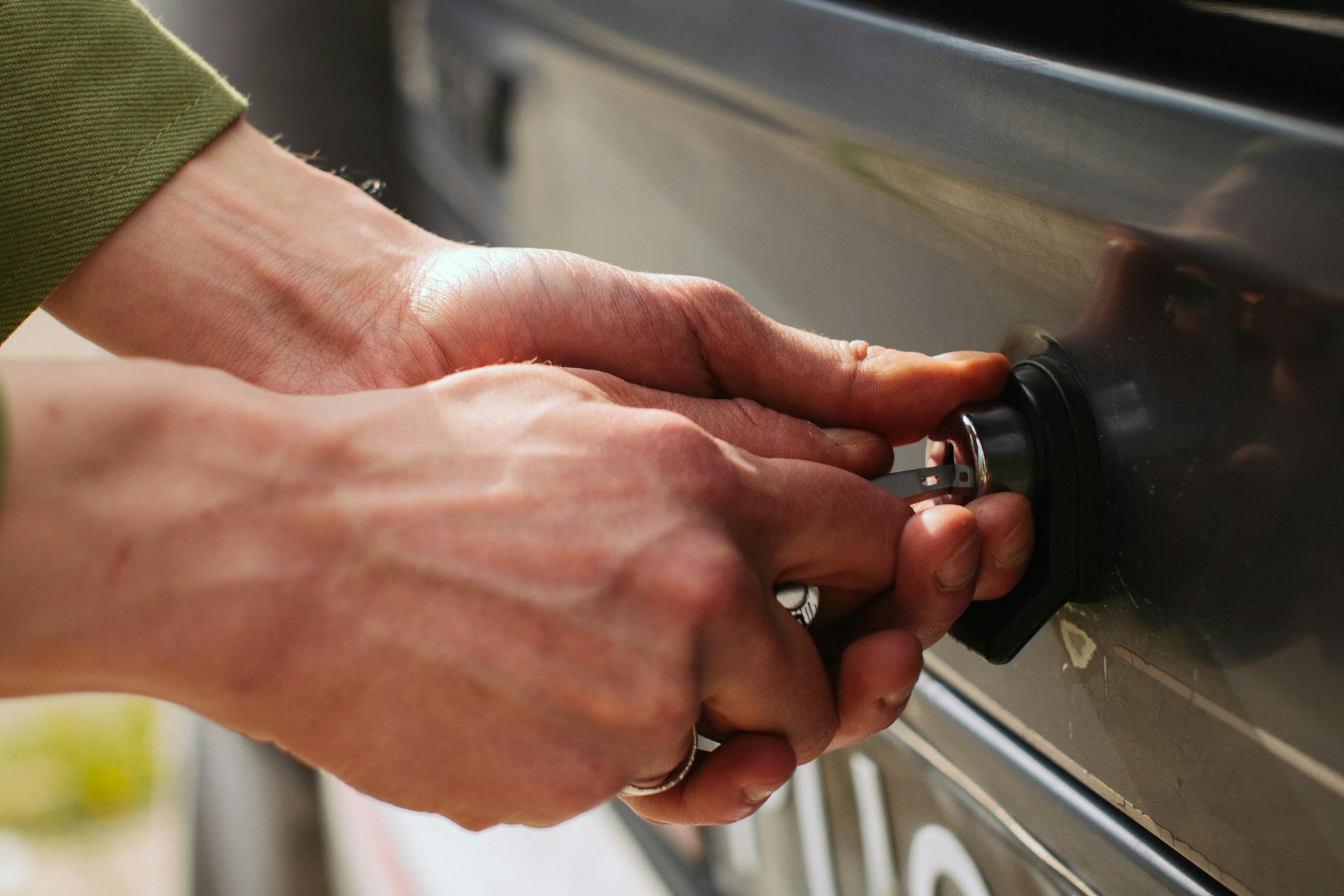 Hands of a Man Unlocking Car Trunk with a Key