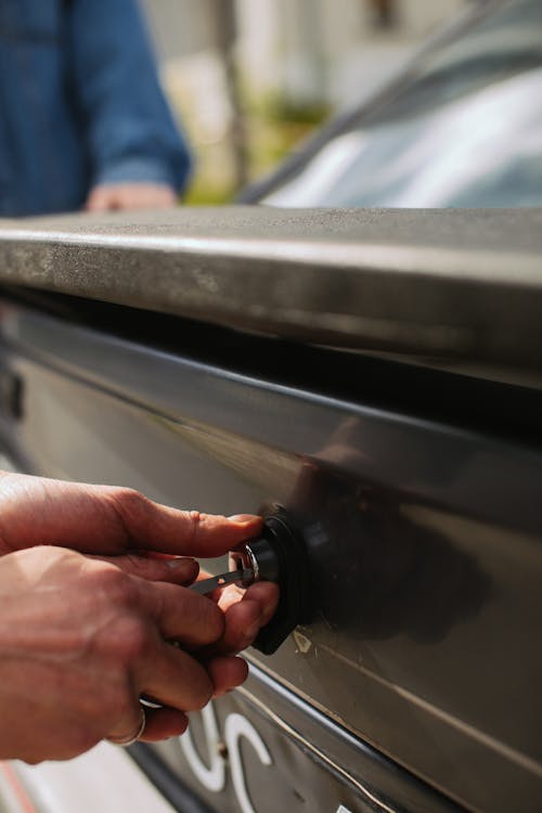 Free Person Unlocking a Car Trunk Stock Photo