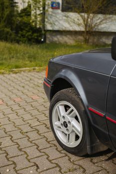 Detailed view of a parked car wheel on a paved surface with grass in the background.