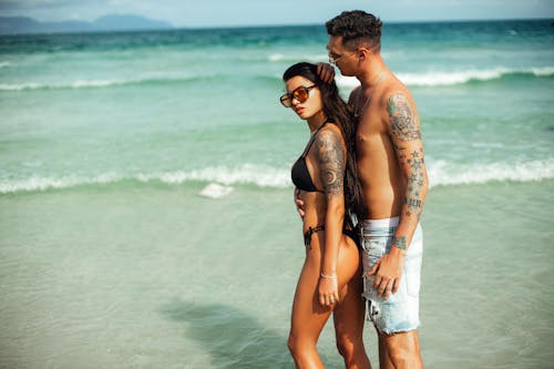 Pareja abrazada mostrando estilo en la playa