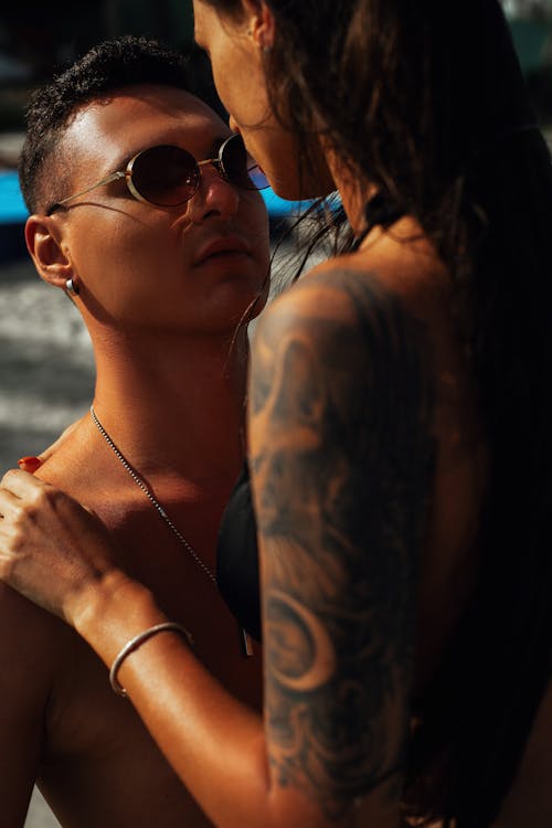 A Man in Sunglasses Looking at the Tattooed Woman