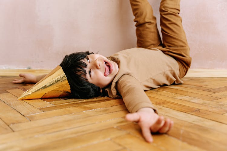 Boy Wearing Party Hat Lying On The Floor