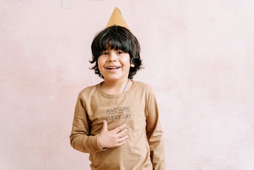 Free A Young Boy Smiling while Wearing a Party Hat Stock Photo