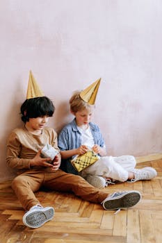 Two children at a birthday party, wearing hats and holding gifts. Perfect for festive occasions.