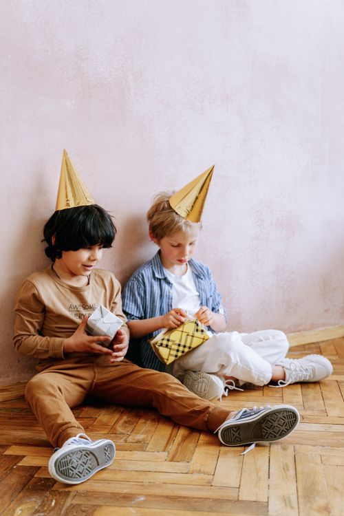 Free Two children at a birthday party, wearing hats and holding gifts. Perfect for festive occasions. Stock Photo