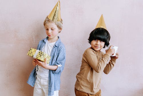 Free Young Boys Wearing a Party Hat while Holding Gifts Stock Photo