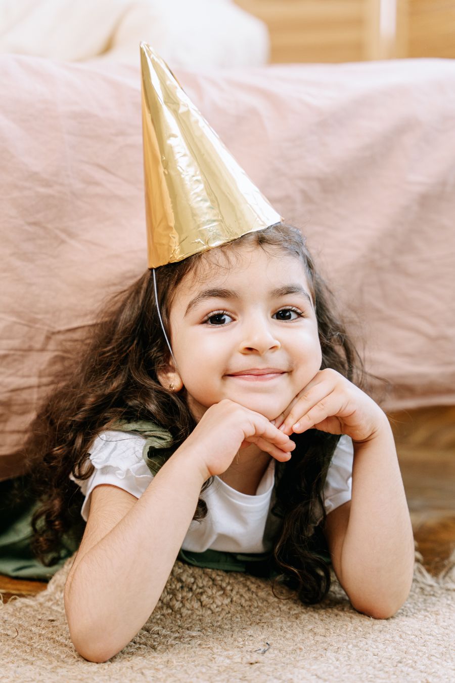 Smiling girl surrounded by confetti and balloons at an indoor celebration