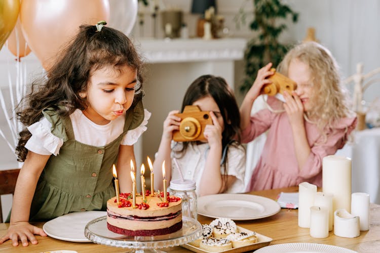 A Girl Blowing Lighted Candles On A Cake