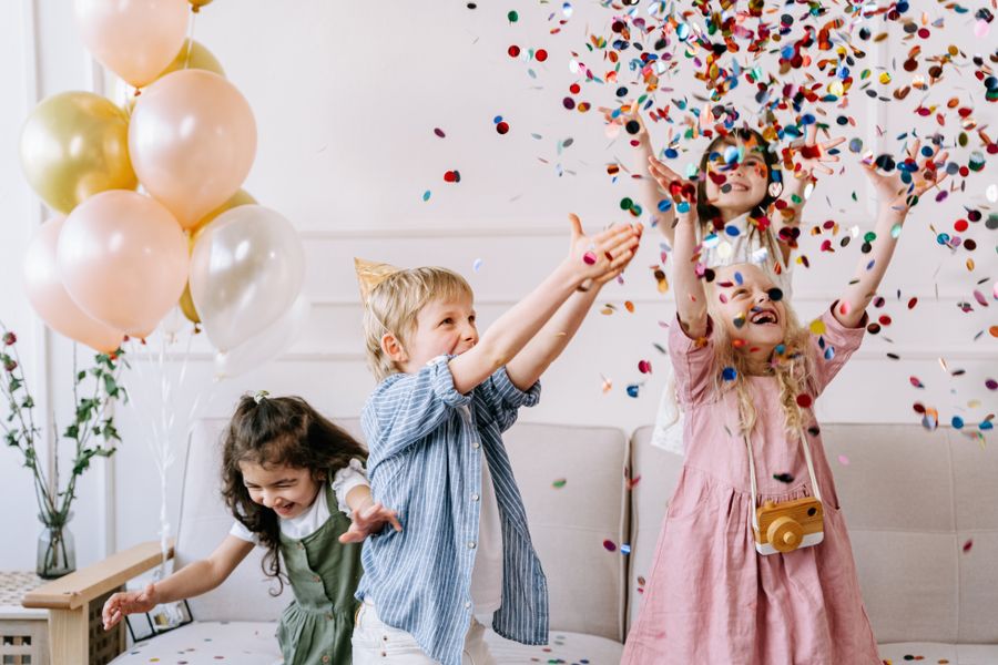 Crianças brincando com confete em festa de aniversário infantil