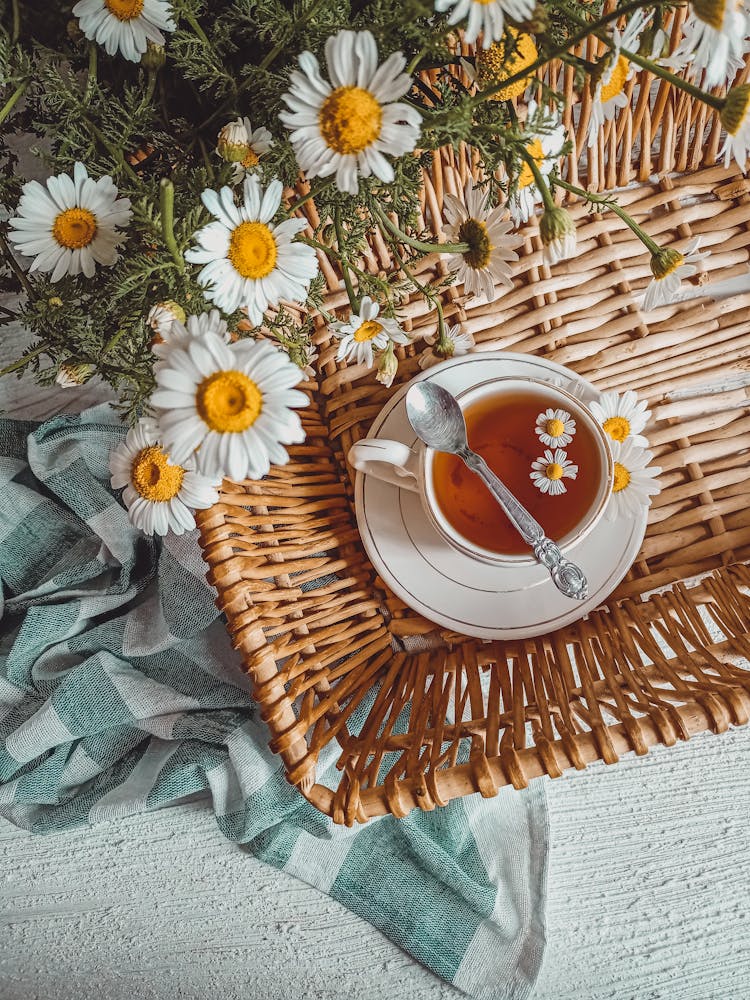 Teacup With Saucer On A Woven Tray Near White Flowers