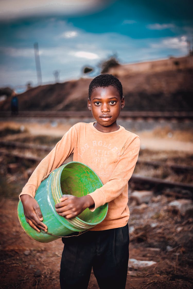 A Boy Holding An Empty Bucket