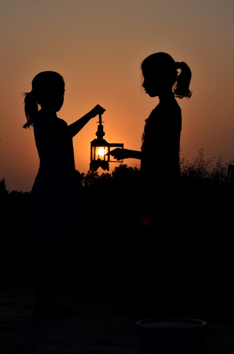 Silhouette Of Girls Holding A Lantern