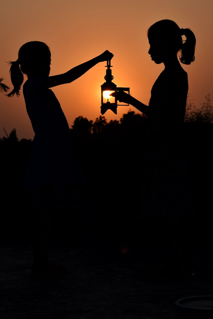 Silhouette Of Two Girls Holding A Lantern