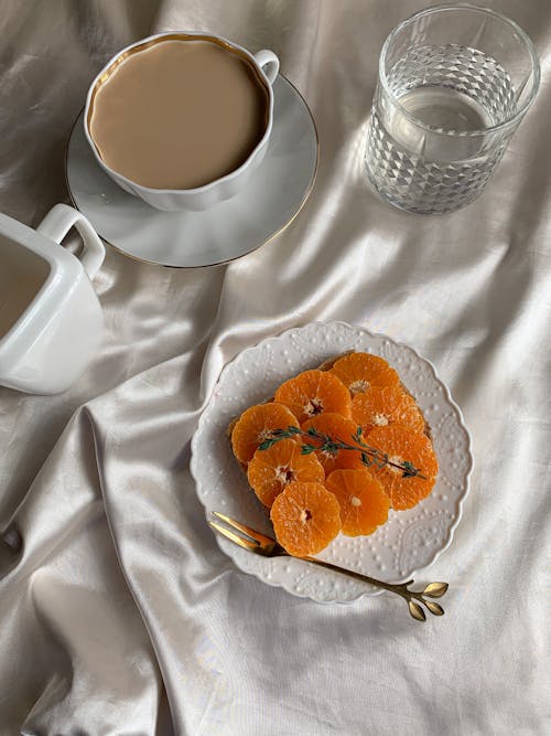 A Sliced Oranges on a Ceramic Saucer Near the Cup of Coffee