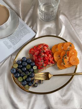 Fresh fruit toasts with blueberries, strawberries, and oranges on a ceramic plate.