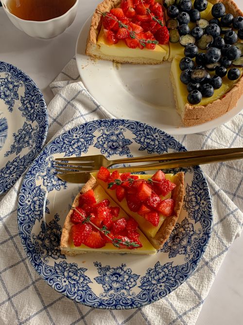Free A delectable fruit tart featuring strawberries and blueberries on elegant blue floral plates. Stock Photo