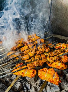 Delicious grilled meat skewers sizzling on a BBQ with aromatic smoke.