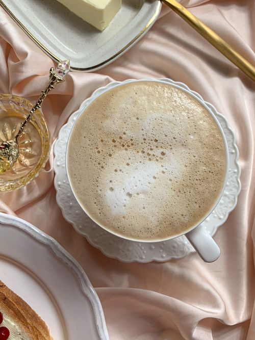 Free Aerial view of a cappuccino on silk fabric with butter and bread, creating a luxurious breakfast scene. Stock Photo