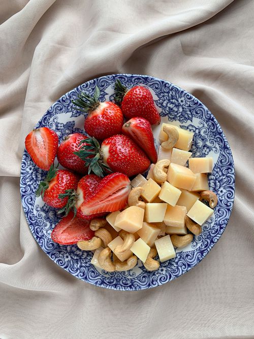 Free Vibrant strawberries, cubed cheese, and cashews arranged on a decorative plate. Stock Photo
