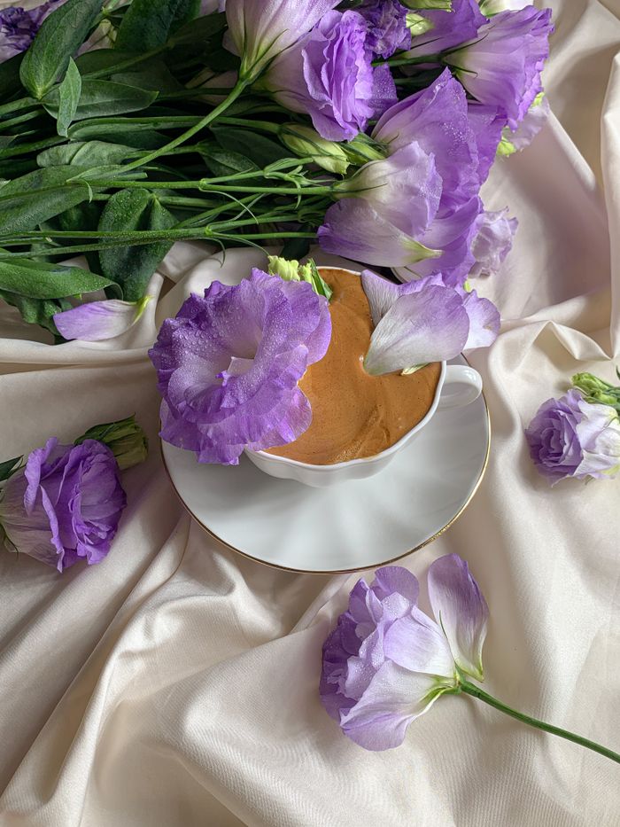 A softly lit cup of coffee with pastel purple flowers