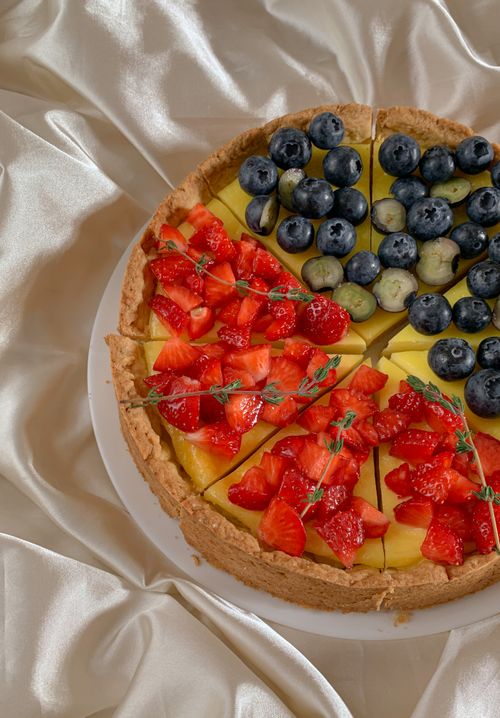 Free A vibrant, fresh fruit tart with strawberries and blueberries on a silky background. Stock Photo