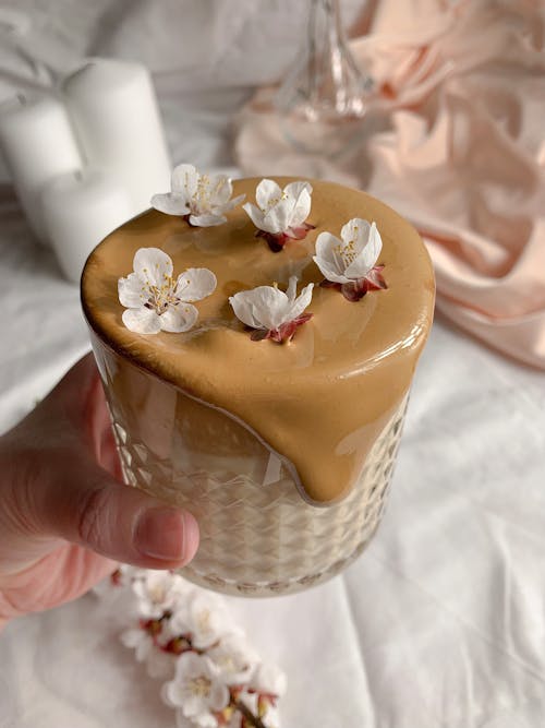 A Hand Holding a Glass with Overflowing Coffee