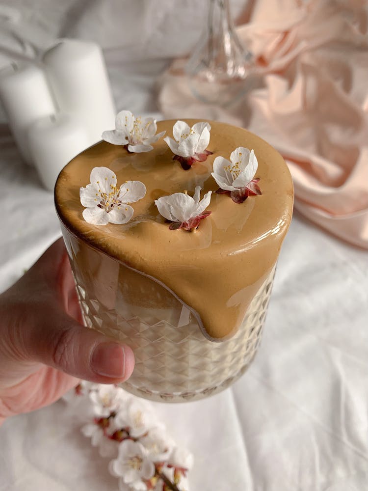 A Hand Holding A Glass With Overflowing Coffee