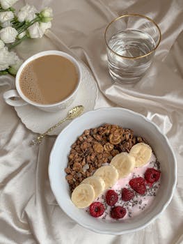 Delicious breakfast with banana, raspberry yogurt, and coffee on elegant table setting.