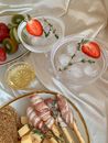 Cocktail Drinks with Slices of Strawberry Beside a Platter of Cheese and Breads