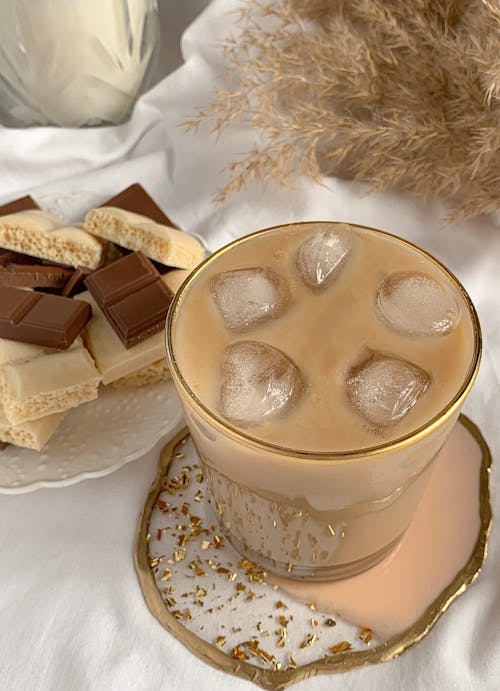Clear Glass Cup with Iced Coffee Beside Chocolates on Saucer