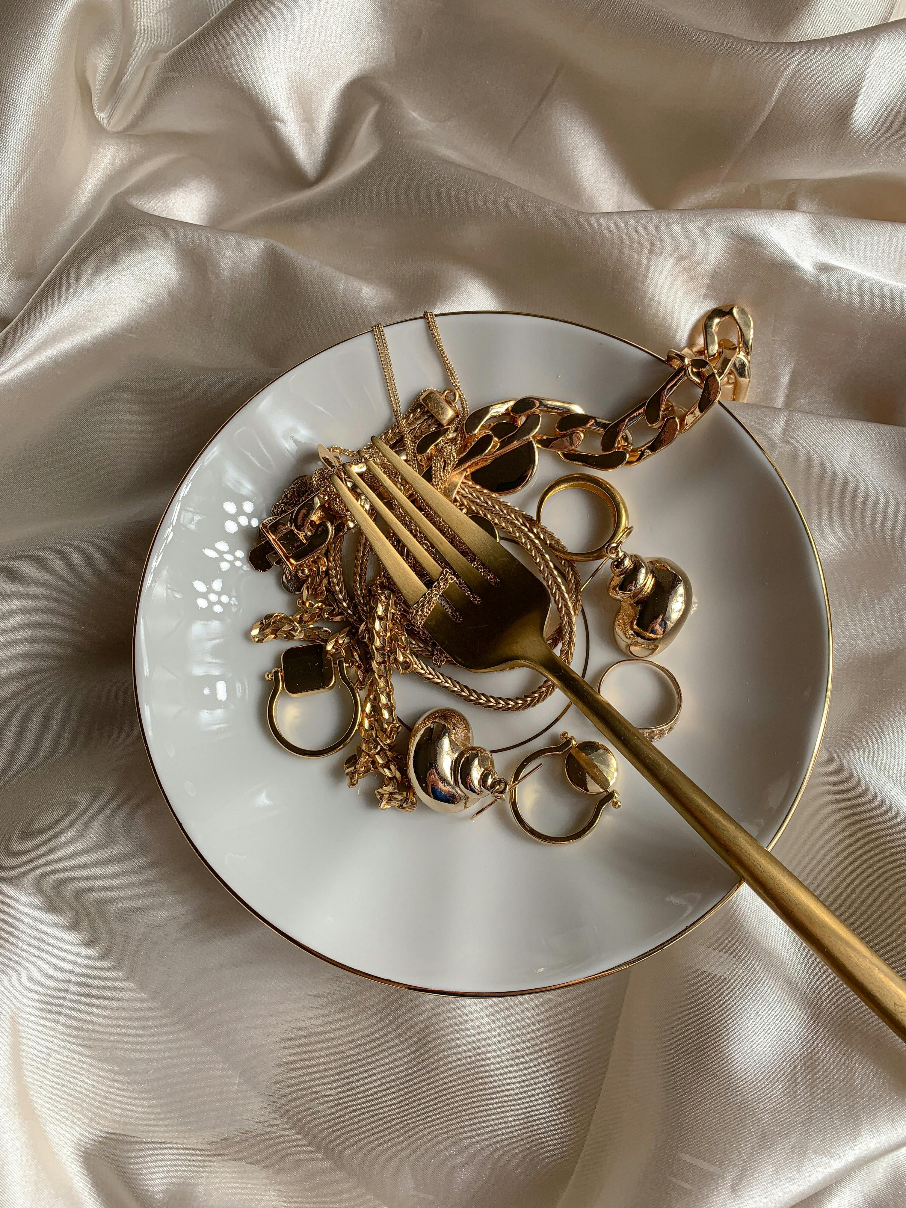 gold jewelries on white ceramic plate