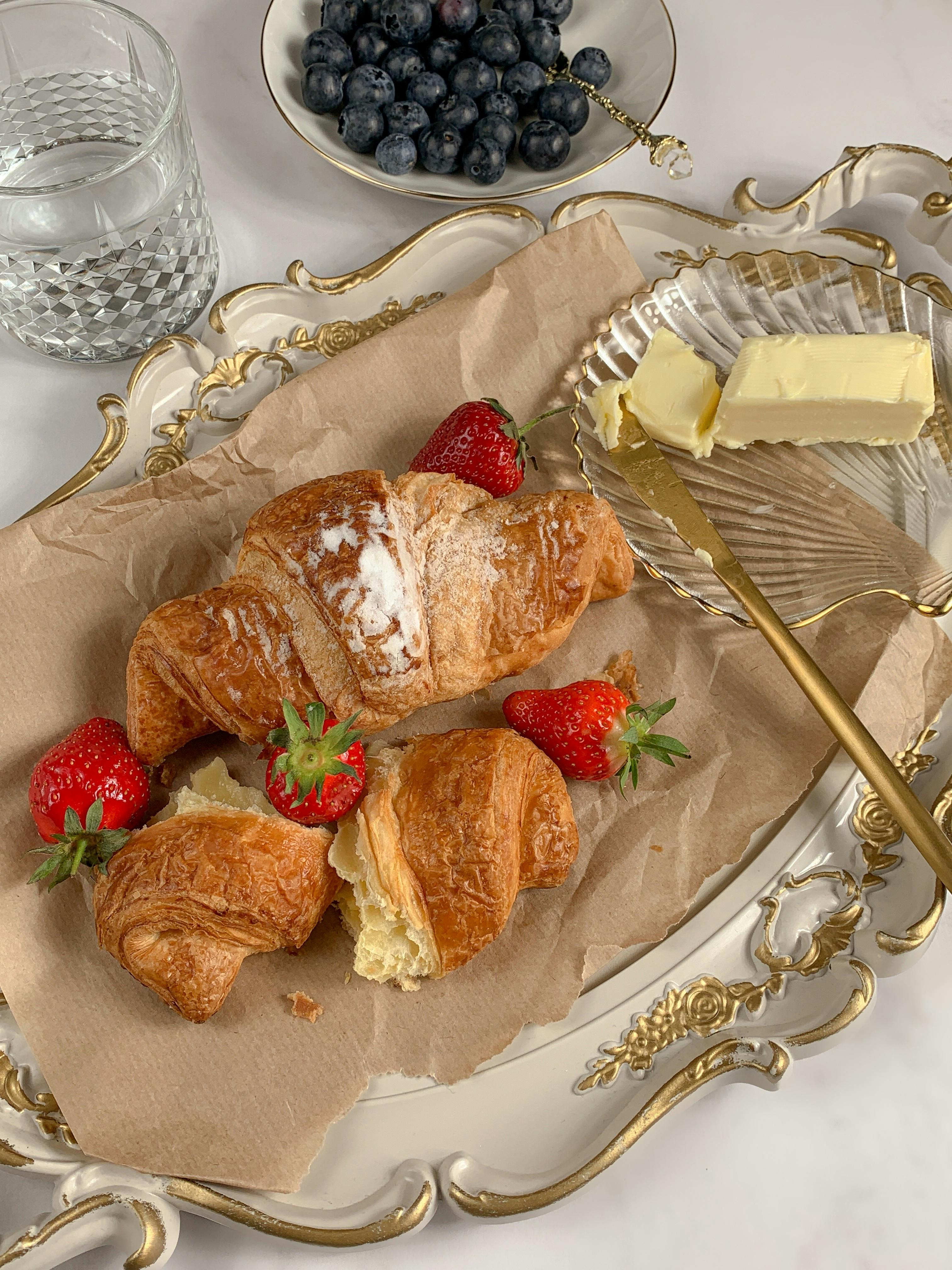 croissants with strawberries and butter on white vintage dish