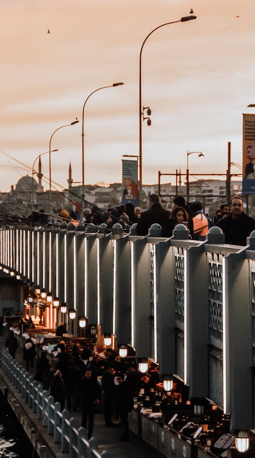 People Walking on and Under Bridge During Sunset