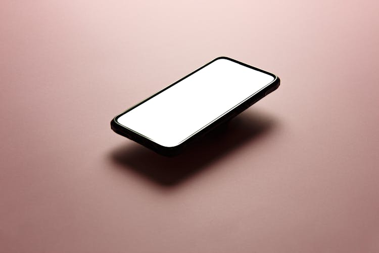 Black Smartphone With White Screen Flowing Above Pink Surface