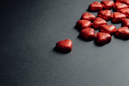 Free A collection of red heart-shaped chocolates arranged on a dark background, perfect for romantic themes. Stock Photo
