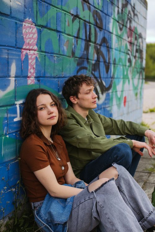 Free A young couple leans against a colorful graffiti wall, embodying urban lifestyle and youthful expression. Stock Photo