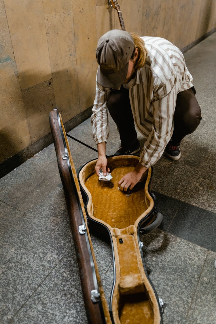 Man Removing The Money In His Guitar Case